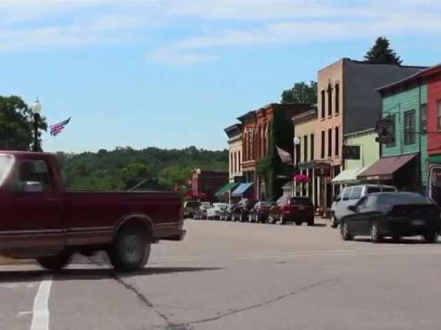 Main Street Lanesboro shows colorful buildings and cars speeding by. 