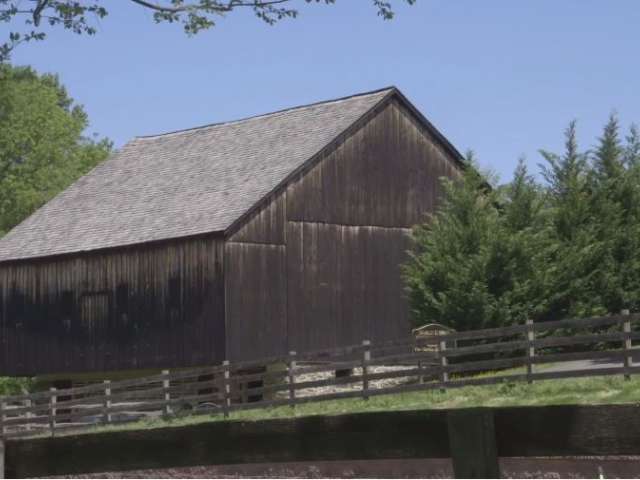 A historic wooden barn in an idyllic farm setting in summer. 