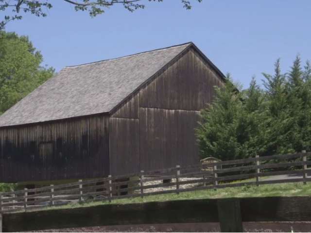 A historic wooden barn in an idyllic farm setting in summer.