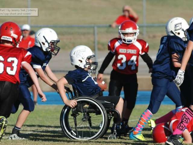 Gabriel Mangus sits in a wheelchair and rolls on the football field.