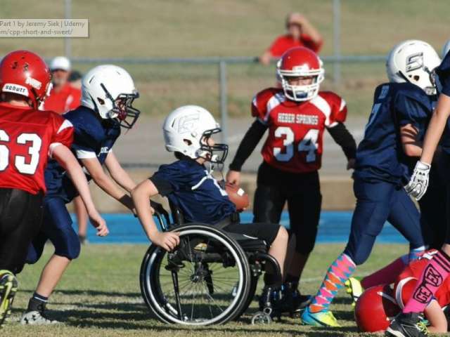 Gabriel Mangus sits in a wheelchair and rolls on the football field. 