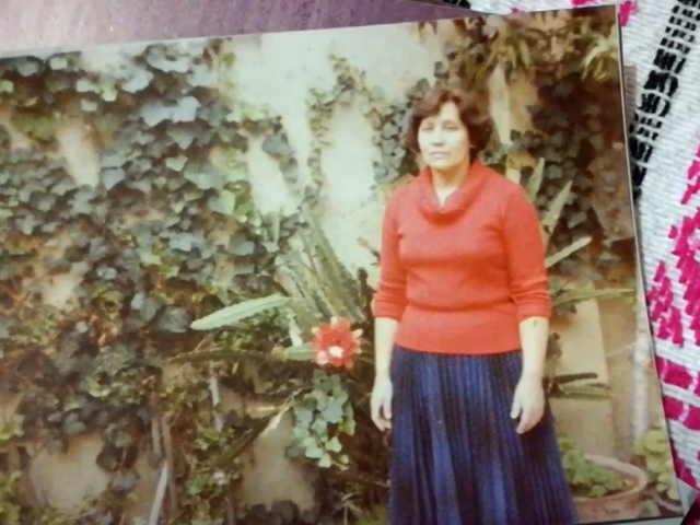 A woman in a red sweater and denim skirt appears in a vintage photograph.