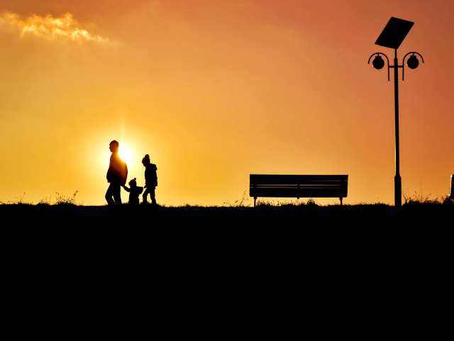 A family walks in the sunset with a bright sky in the background. 