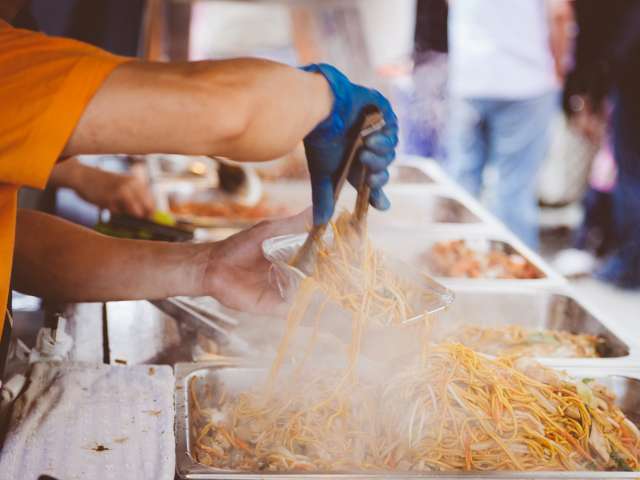 A man serves up noodle dishes at a festival. Pexels stock photo