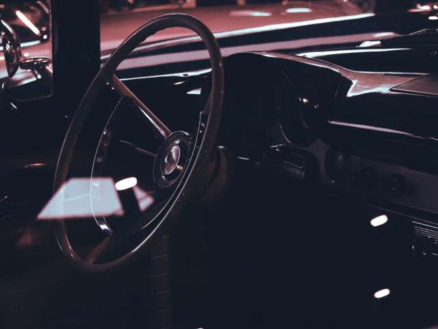 The interior of a vintage car showing its steering wheel. Pexels stock photo.