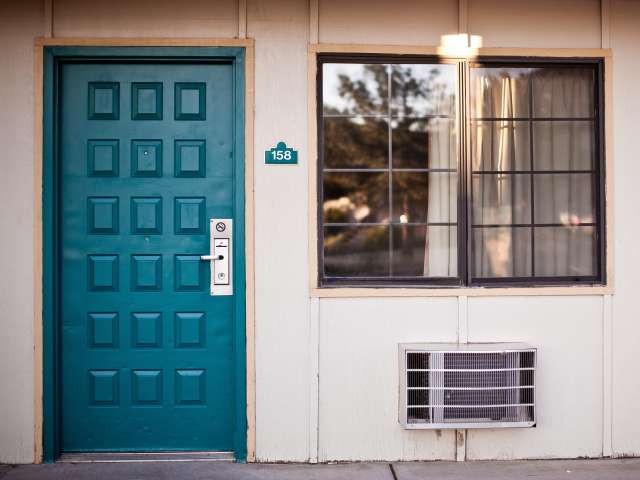 The blue-green entry door of a motel. Pexels stock photo