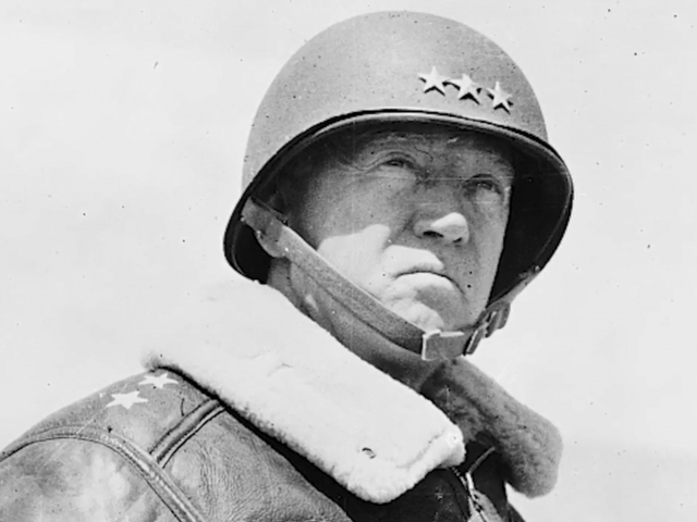 General George S. Patton wears a helmet and leather jacket with a heavy cotton collar.