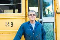 Randy Henson stands in front of a school bus. 